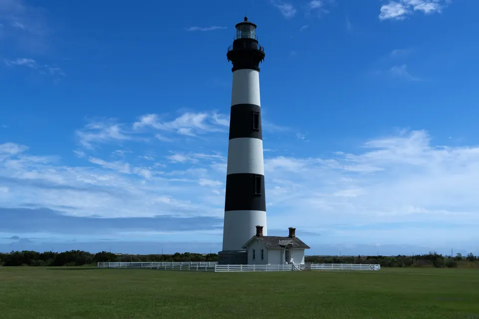 The black and white banded Bodie Island lighthouse under a blue sky