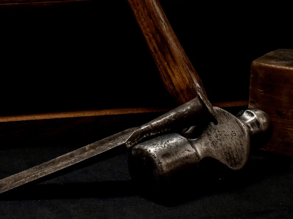 An old hammer and chisel resting in deep shadow