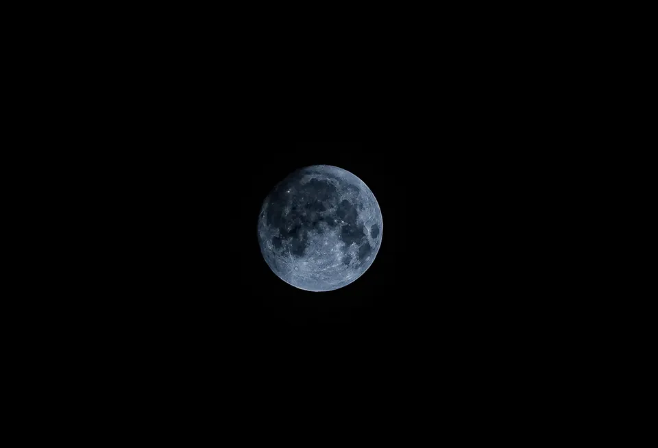 A small, bright moon in a black sky