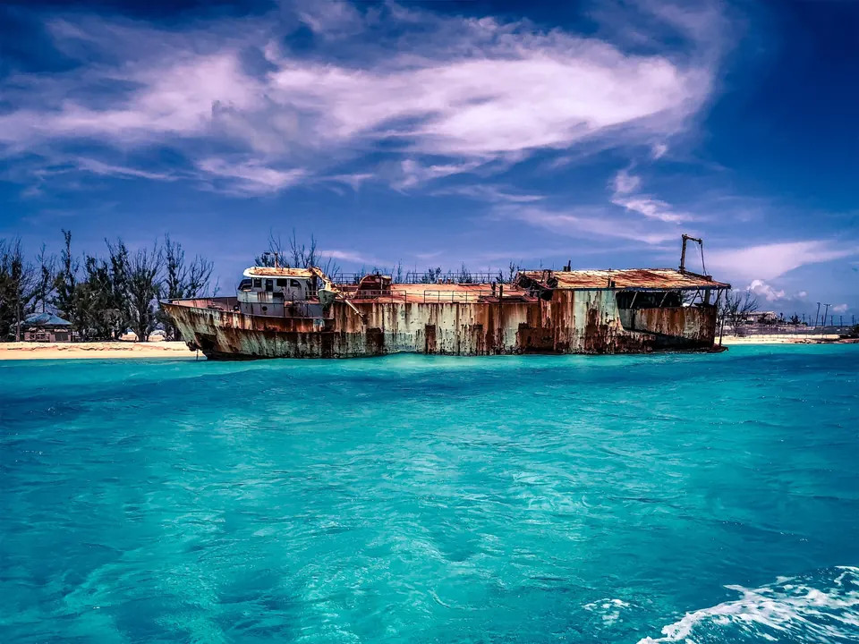 A rusted shipwreck resting in turquoise water under a dramatic sky